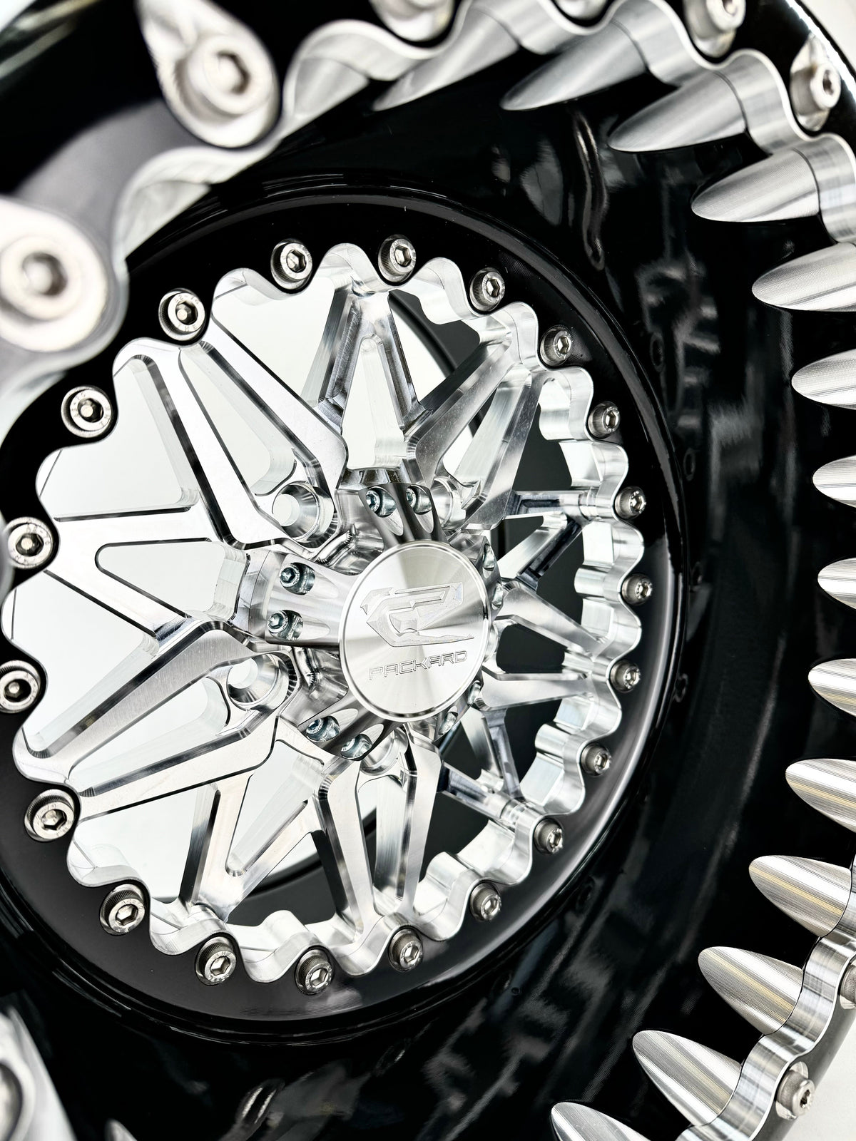 Close-up of a Packard Impact silver beadlock UTV wheel with a black barrel.