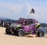 Hostile H333 Glamis Beadlock wheels on a purple and green Polaris RZR Pro R kicking up sand at a dune event. Hostile gallery.