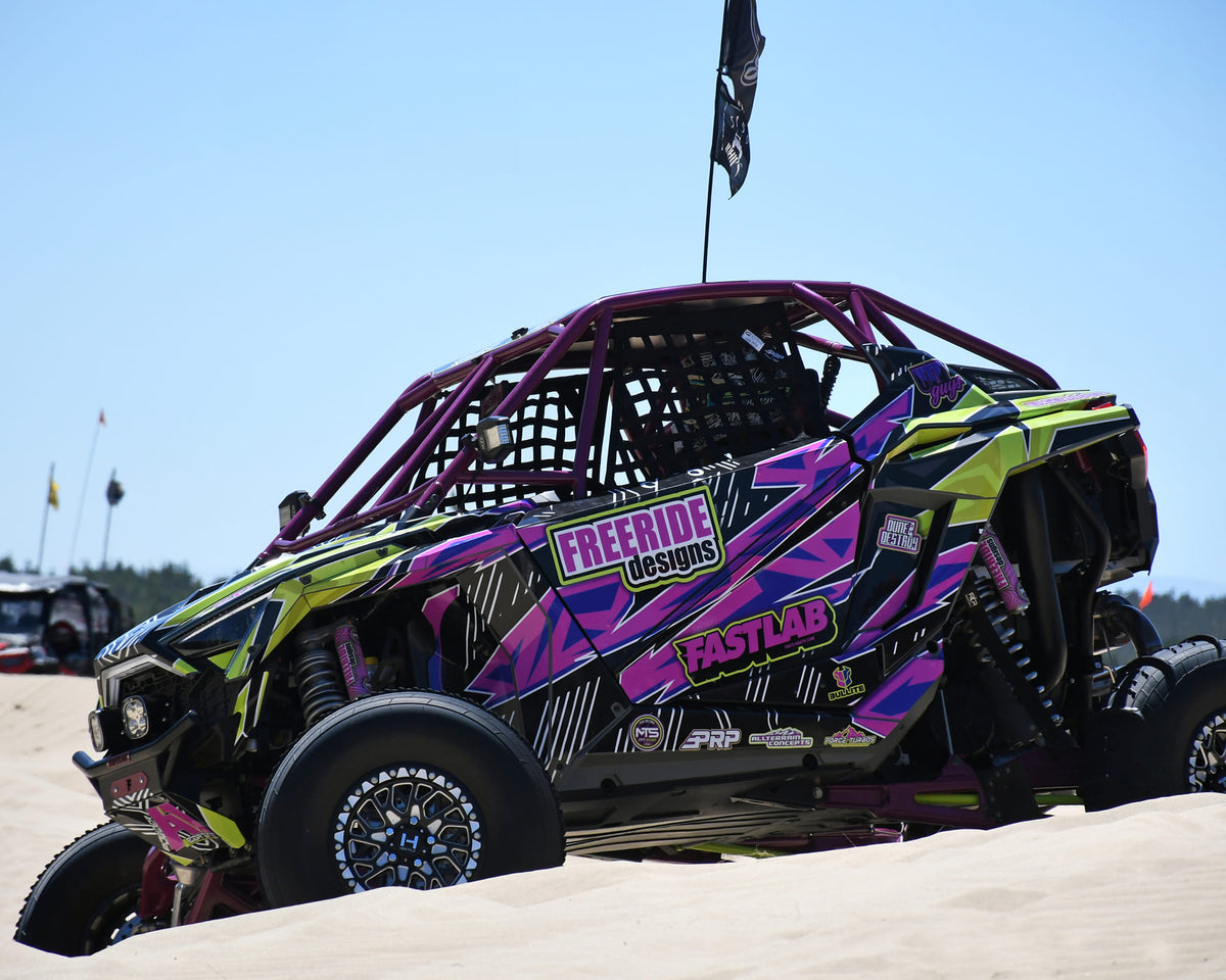 Hostile H333 Glamis Beadlock wheels installed on a custom-wrapped Polaris RZR Pro R at the dunes. Hostile manufacturer gallery.