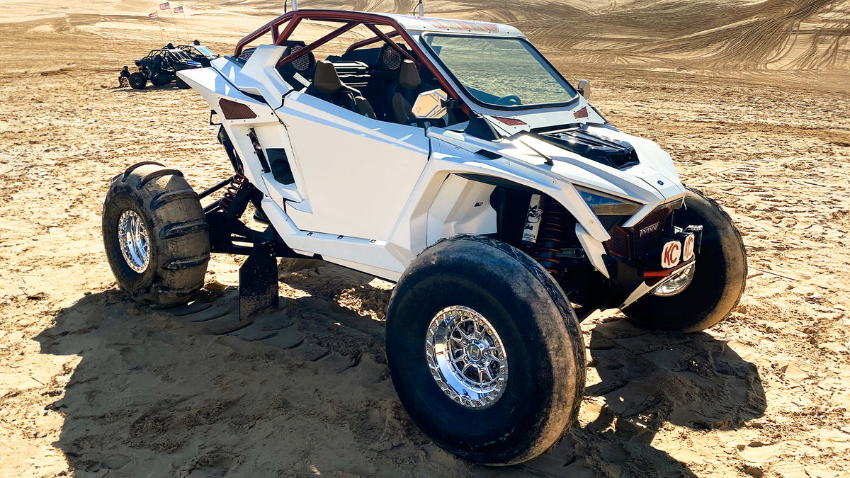Hostile HF32 Rival Beadlock polished wheels installed on a white Polaris RZR Pro R in the dunes. Hostile gallery photo.