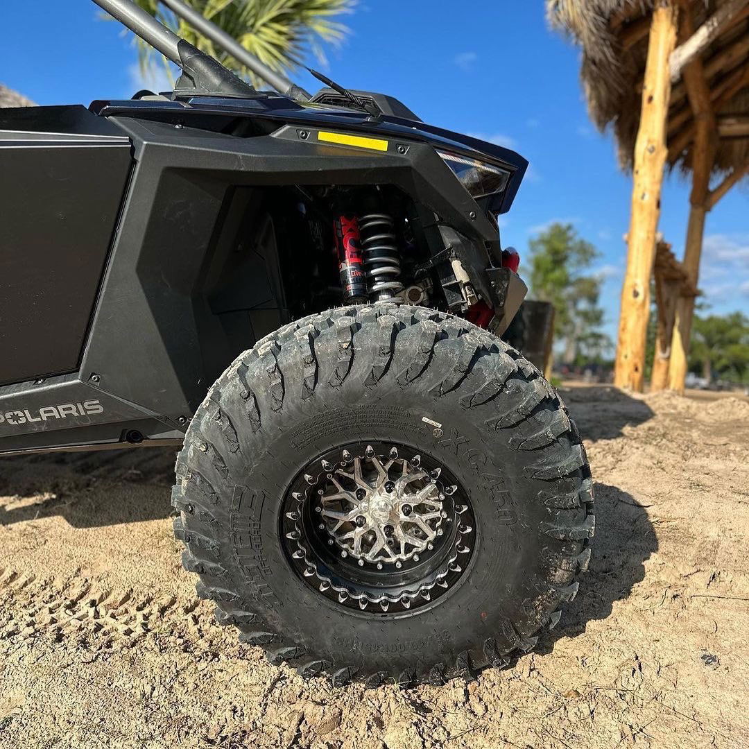 Packard Impact silver-center, black-barrel beadlock wheel installed on a Polaris build with an off-road tire. Real build photo from Packard Performance; cap and setup details may vary.
