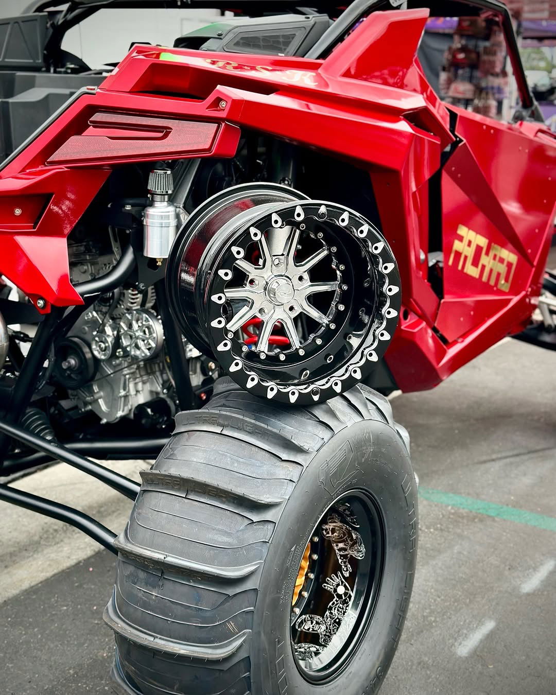 Packard Element silver beadlock wheel with a black barrel displayed beside a red Polaris RZR Pro R.