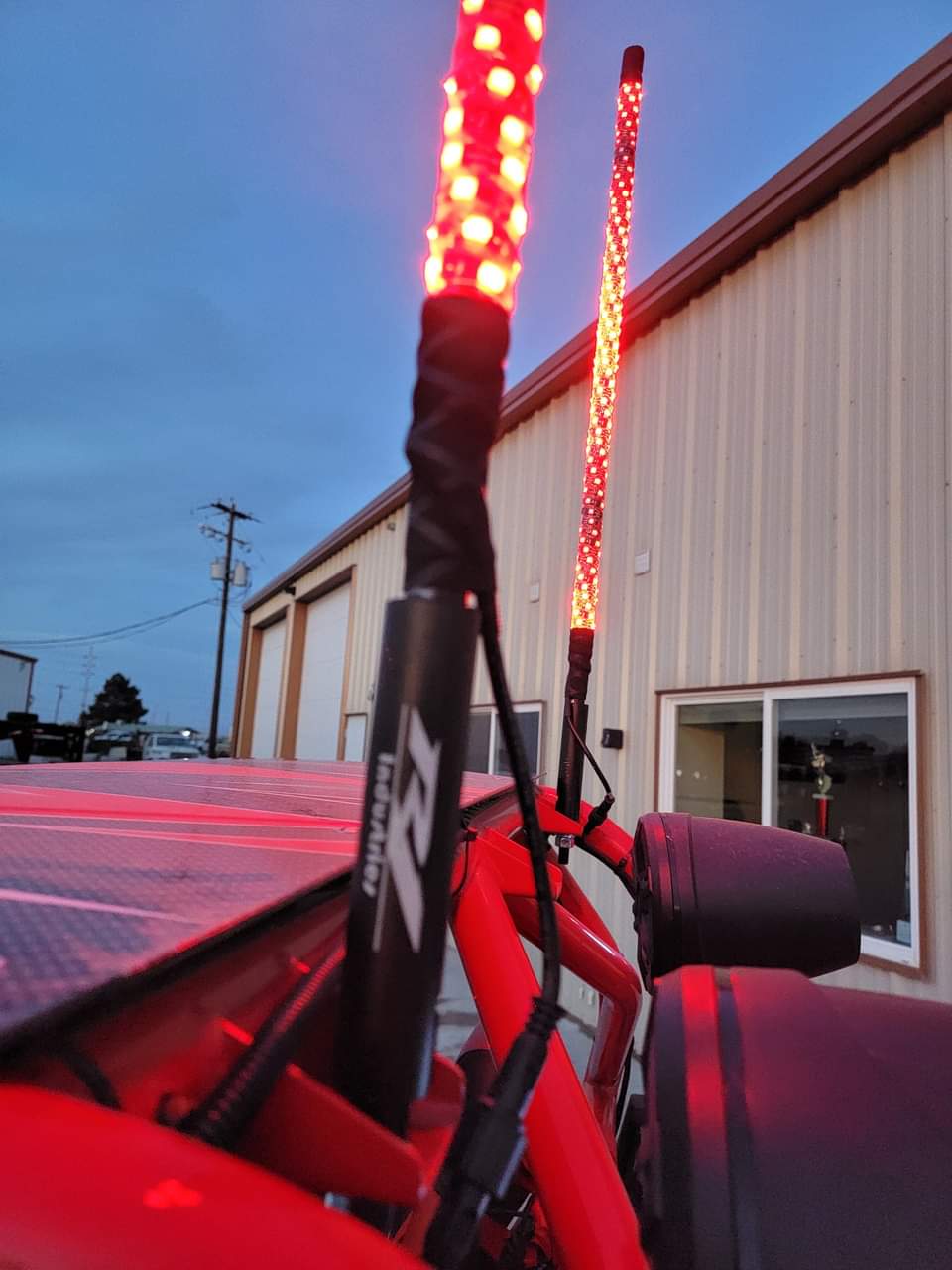 Red LED light whips on a vehicle with a building in the background