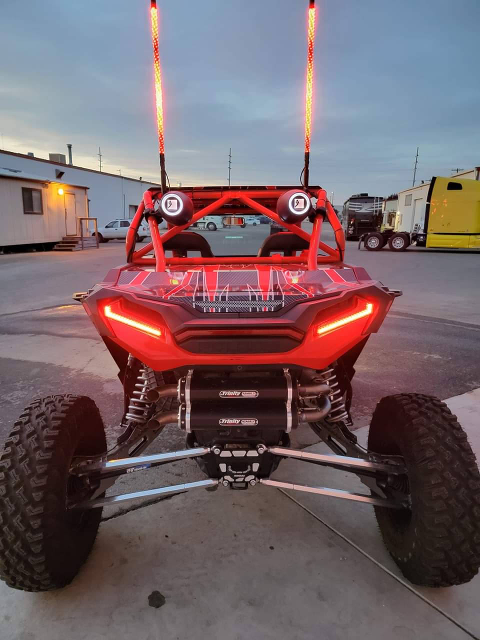 Red off-road vehicle with visible suspension and lights on a concrete surface.