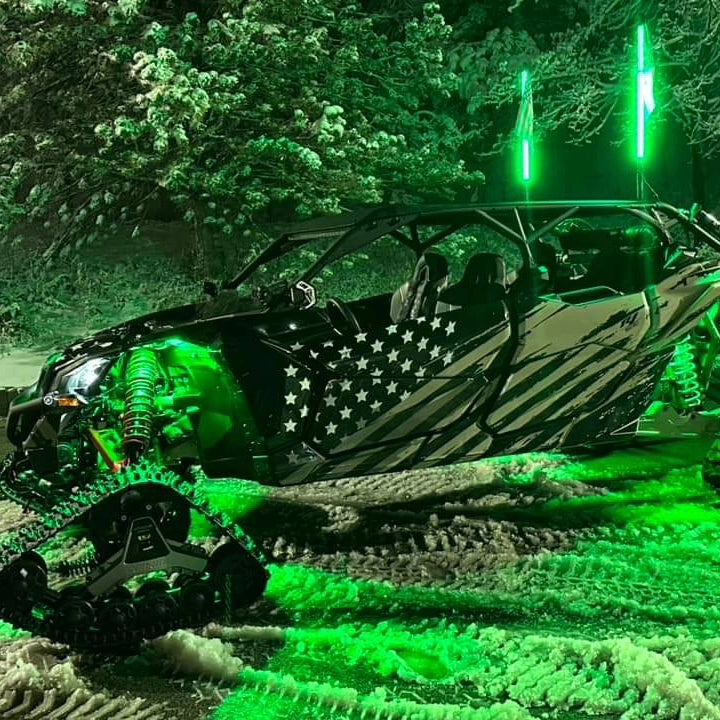Off-road vehicle with American flag design on a forested trail at night.