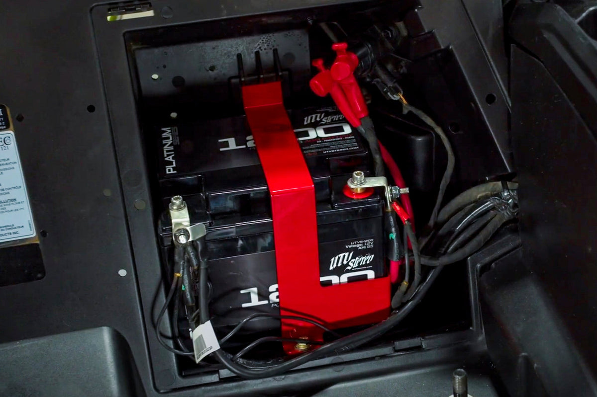 Manufacturer installation photo: UTV Stereo UTVS1200 big battery and red mounting bracket in a Can-Am X3; other vehicle equipment not included